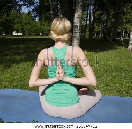 blonde real girl doing yoga in green park on grass