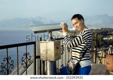 young real woman looking through telescope at sea viewpoint in Ataturk park, sunny morning