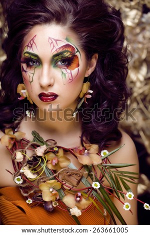 beauty woman with face art and jewelry from flowers orchids close up