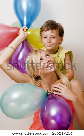 pretty real family with color balloons on white background, blond woman with little boy on birthday party isolated