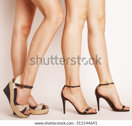 two pair of woman legs in hight heels shoes isolated on white
