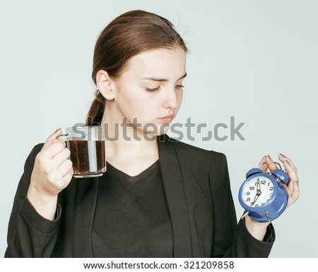 young beauty woman in business style costume waking up for work early morning on white background with clock dreanking coffee close up