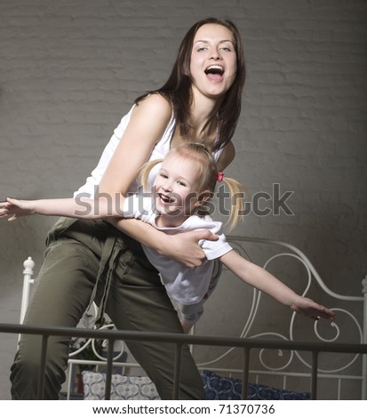 portrait of happy mother and her daughter playing in bad