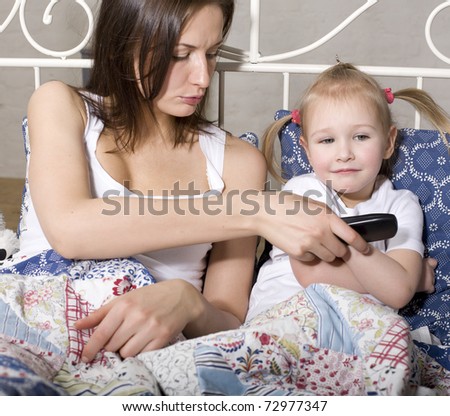 portrait of happy family, mother and daughter in bed watching television