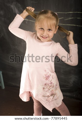 portrait of little cute girl with chalk writing on blackboard