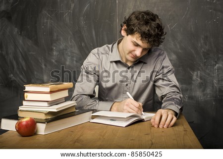 The young emotional student with the books and red apple in class room, at blackboard