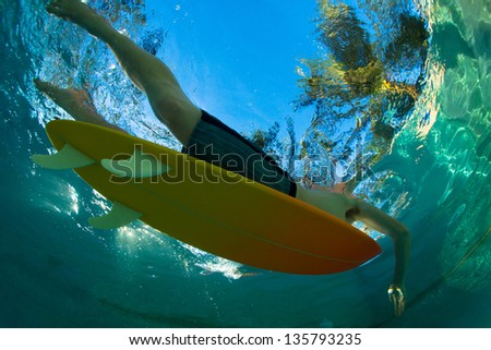 Young surfer paddling through the ocean