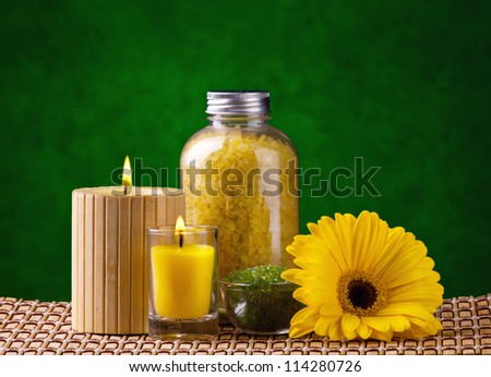 spa cosmetics and  yellow flower on bamboo mat and green background