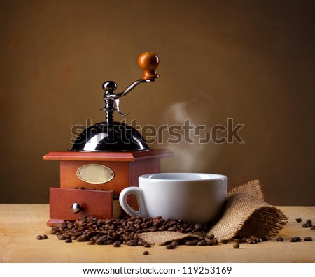 coffee mill, coffee cup and coffee beans on brown background