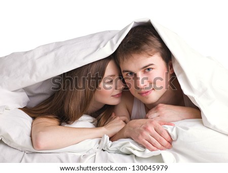 young man and beautiful girl in a bed under blanket on white background