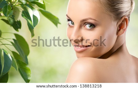 youth smiling nude woman with green eyes  and green leaf on green blurred background