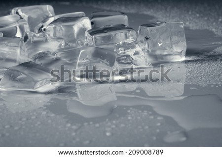 pile of different ice cubes on reflection table with water drop, light grey color