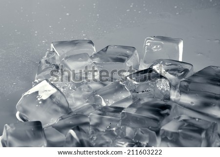pile of different ice cubes on reflection table with water drop, on misted light grey surface