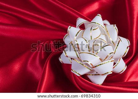 white gift bow on an elegance red silk background