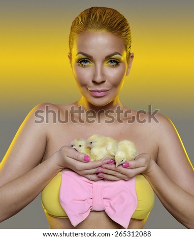 smiling woman with three yellow chickens . Holding chicken in hand