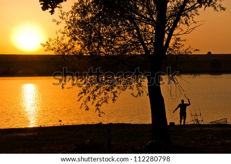 fishing at the sunset, man feeding the fish at the sunset, landscape image