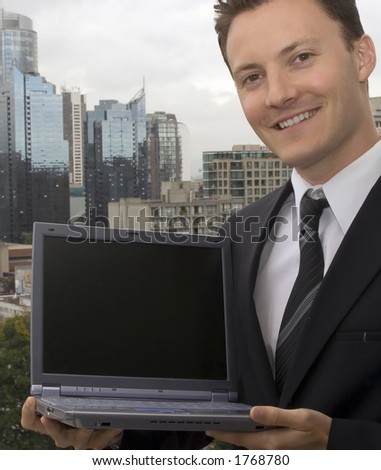 A businessman is showing off a laptop with a blank screen.