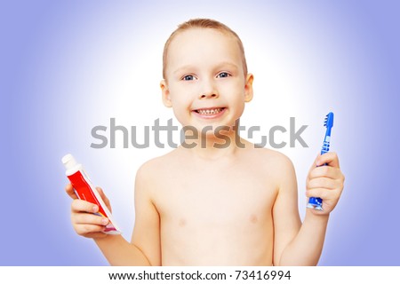 The little boy shows a tooth-brush and a tube with tooth-paste