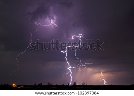 Lightning bolts lighting up the sky over a rural landscape