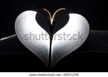 Heart shape formed in the pages of a book lit from behind