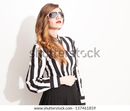beautiful model with high waisted pleated skirt wearing eyeglasses posing on white background