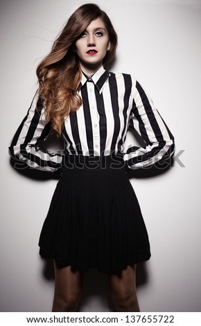 young beautiful fashion model with lined black and white shirt posing on white background