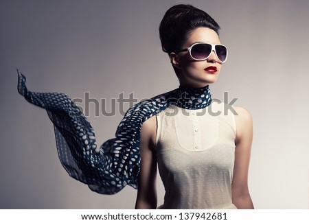 beautiful young model with her scarf flying posing on gray background