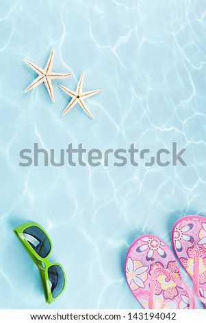 two starfishes, sunglasses and flip flops under water on blue background