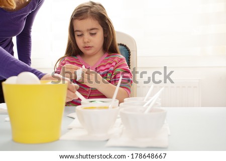 cute little girl trying to dye the eggs for easter