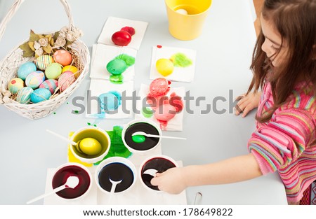 cute little girl trying to dye the eggs for easter