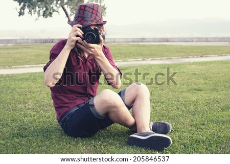 retro filtered photograph of a hipster guy with an analog camera