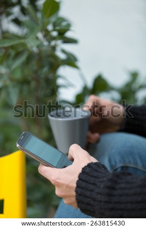 hipster guy using his smart phone outdoors and relaxing.shallow depth of field with focus on the phone