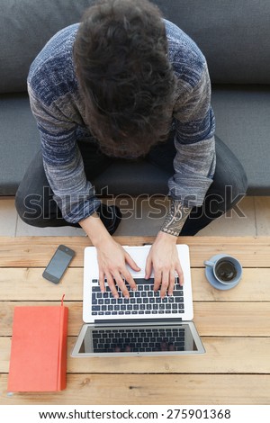 young guy with tattooed arm using a laptop