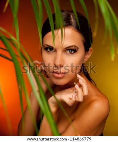 close-up studio portrait of young beautiful tanned woman with long acrylic leopard nails and makeup