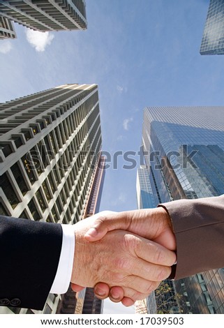 Businessman handshake against the towering skyscrapers of downtown