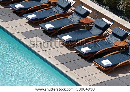 Stylish cushioned chaise longues around a modern pool on a rooftop
