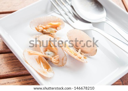 Stir fried roasted chili paste clams on white plate with spoon and fork