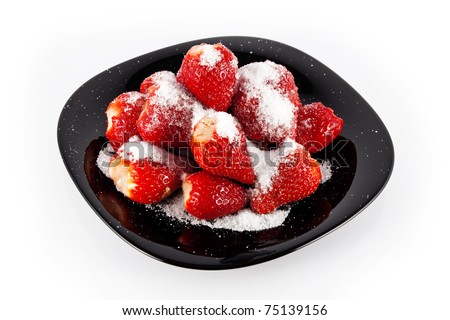 Juicy red strawberries, sprinkled with sugar, on the black plate.