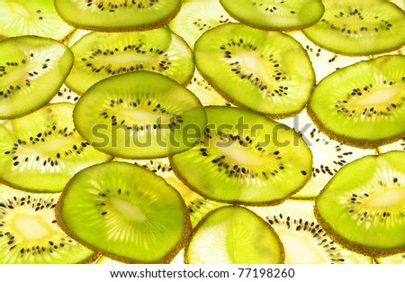 Cut slices of kiwi, illuminated by strong light on glass substrate.