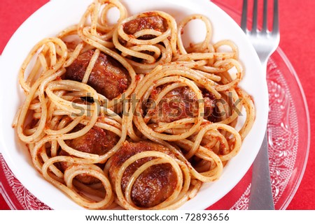 Pasta with meatballs and tomato sauce on red background