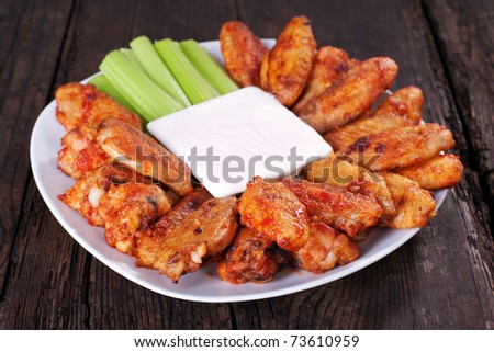 Buffalo chicken wings on plate with blue cheese sauce and celery.