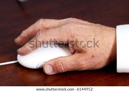 Elderly hand using a computer mouse on a desk