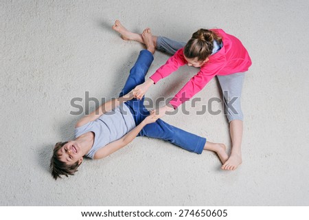 Two young children are stretching on white carpet