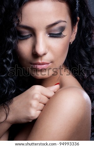Portrait of a young brunette lady with her eyes closed wearing dark make-up with long lashes