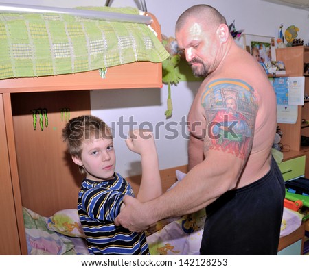 KIEV, UKRAINE - 20 MARCH 2013: The World\'s Strongest Man Vasyl Virastuk checks a biceps of his son Adam in own flat on March 20, 2013 in Kiev, Ukraine.