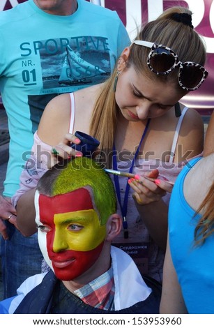 KIEV, UKRAINE Â?Â? 01 JULY 2012: The unknown painter drawS national flags on faces of unknown football fans on Euro-2012 on July 01, 2012 in Kiev, Ukraine.
