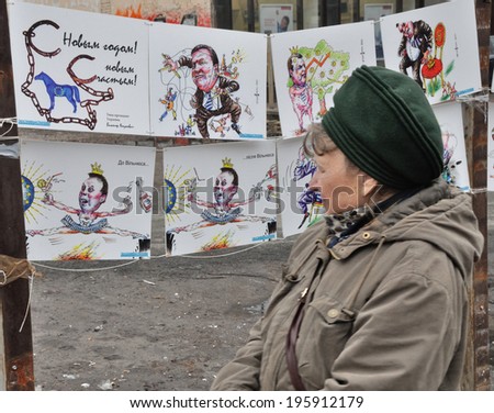 KIEV, UKRAINE  - JANUARY 24, 2014: Unknown woman watches the irony exhibition of picture tribute to political regime of Ukrainian president V.Yanukovych on January 24, 2014 in Kiev, Ukraine.