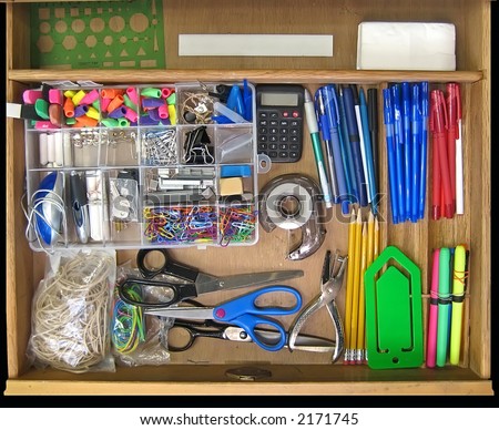 Open teacher's desk drawer full of supplies.