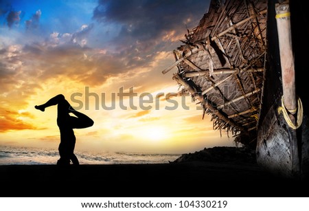 man silhouette doing shirshasana head stand pose on the beach near the fisherman boat at sunset background in Varkala, Kerala, India