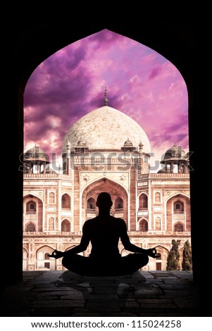 Yoga meditation in lotus pose by man silhouette in arch at Humayuns tomb and purple sky background in New Delhi, India